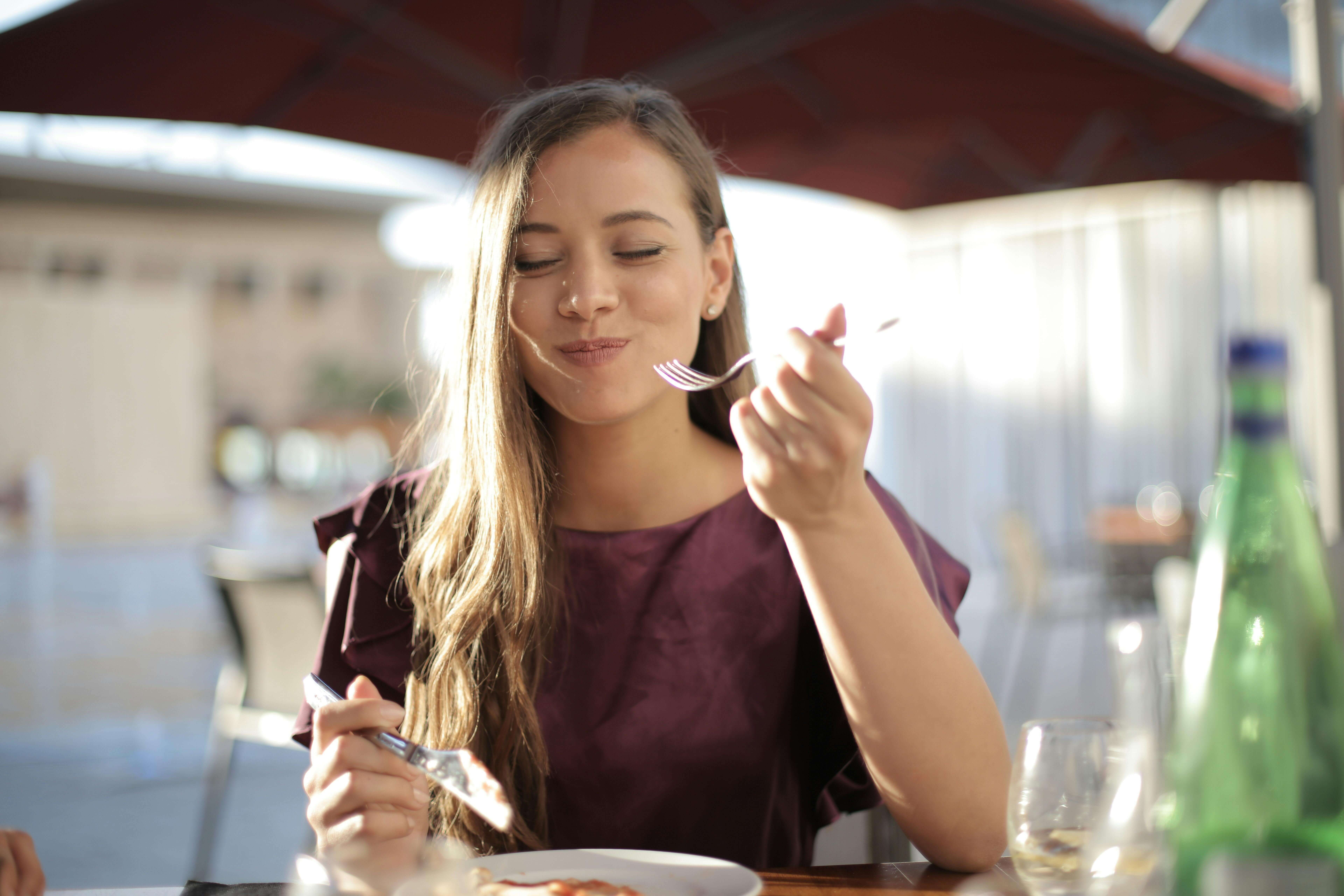 Woman savoring bite of food and looking joyful